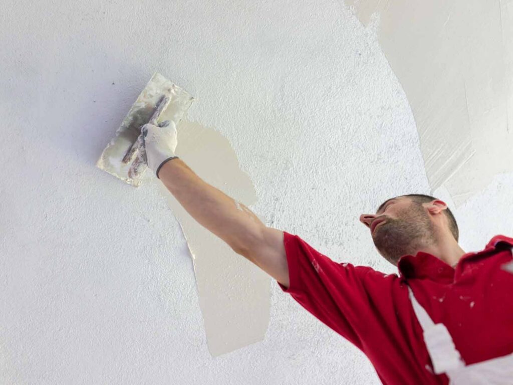 Tradesman applying plaster stopping compound to a ceiling during interior plastering and GIB® stopping work