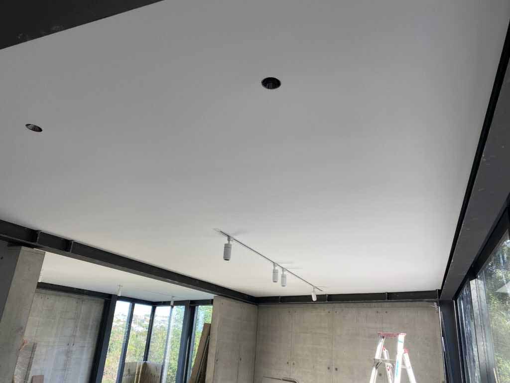 Flat white plasterboard ceiling with recessed downlights after fixing and stopping are complete